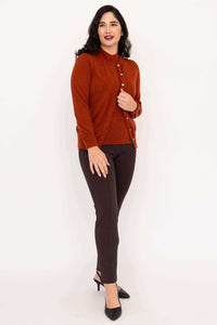 Woman in rust Merino wool cardigan with one hand on open cardigan