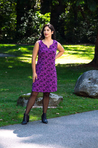 Woman outdoors in a sleeveless purple patterned shift dress and black boots