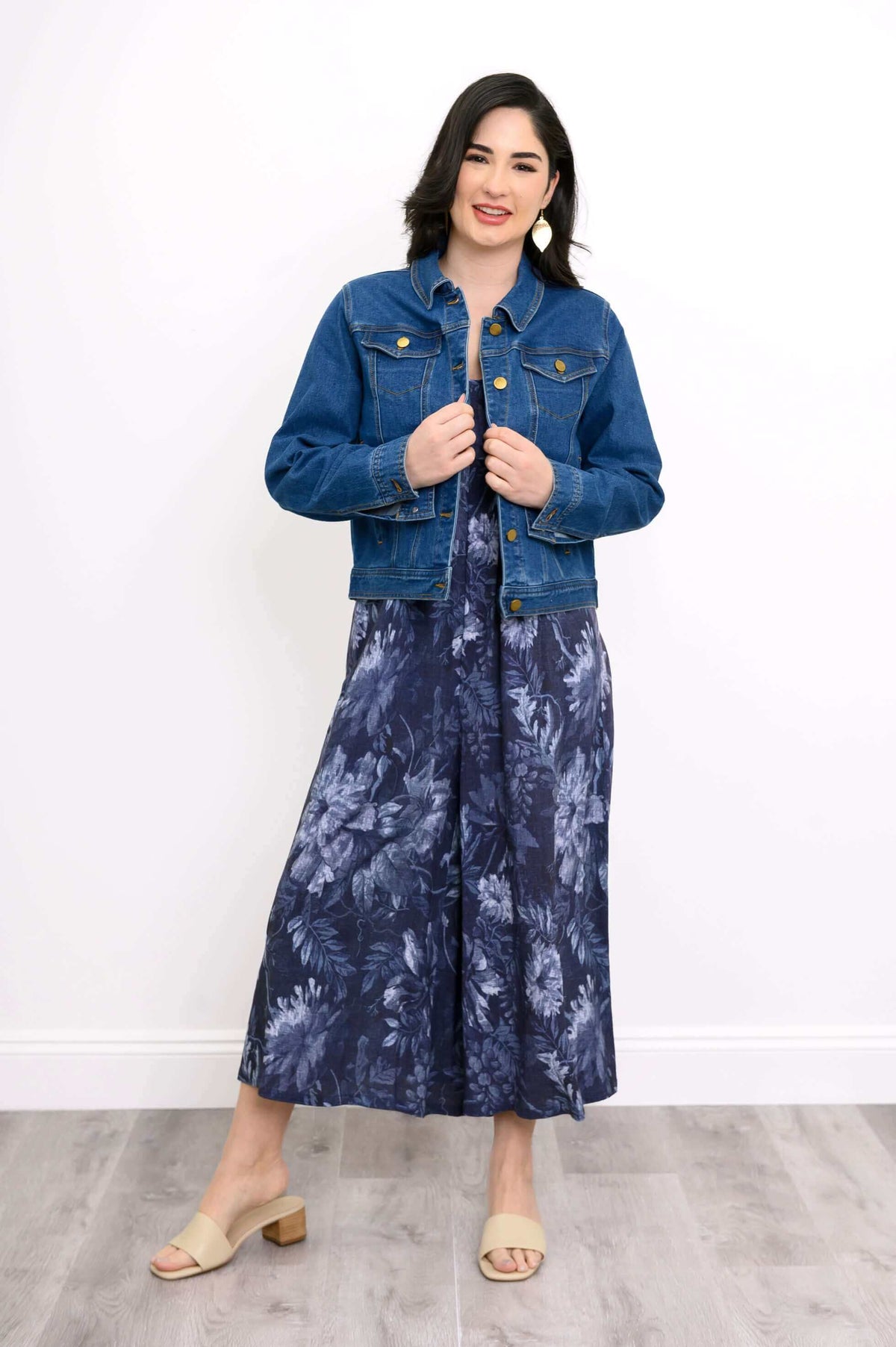 Full body front view of woman wearing denim jacket on a blue floral print outfit