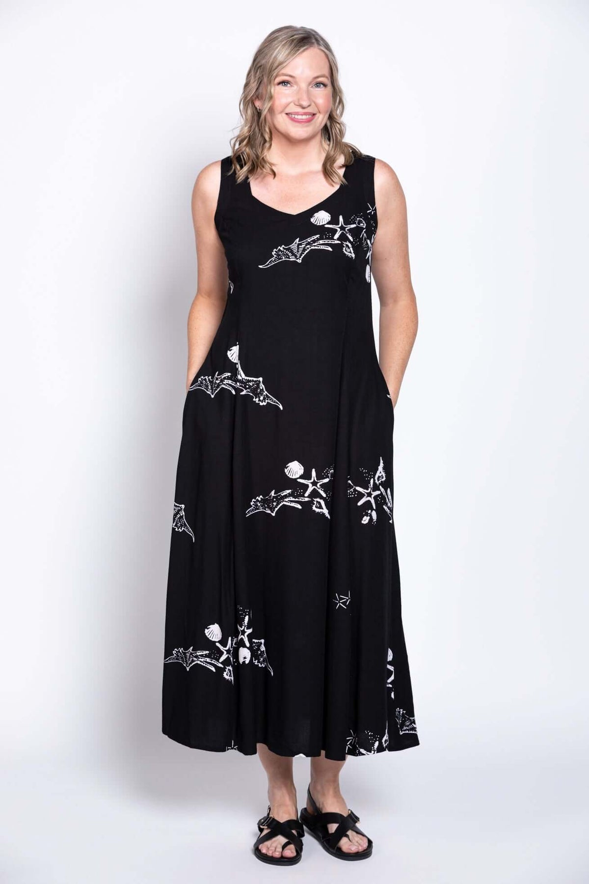 Woman posing in a black dress with white marine-inspired prints and hands in pockets
