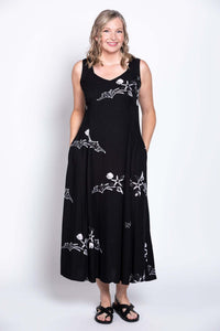 Woman posing in a black dress with white marine-inspired prints and hands in pockets