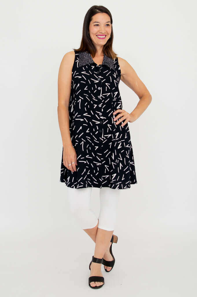 Woman posing in black A-line tank dress with white streak pattern and button details