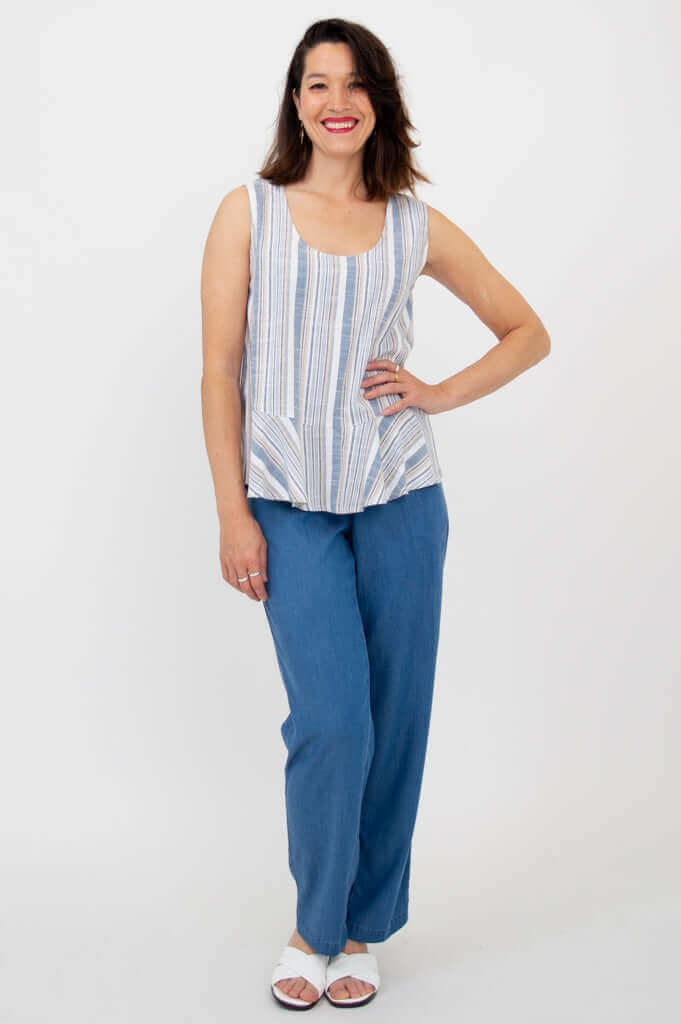 Smiling woman posing in a blue and white striped tank top and blue pants