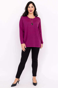 Woman posing in fuchsia sweater and black pants styled with necklace and heels