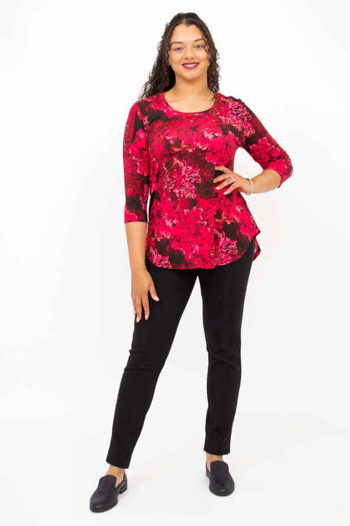 Woman posing in fuchsia swirl bamboo top, hands by side, against white background
