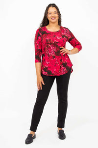 Woman posing in fuchsia swirl bamboo top, hands by side, against white background