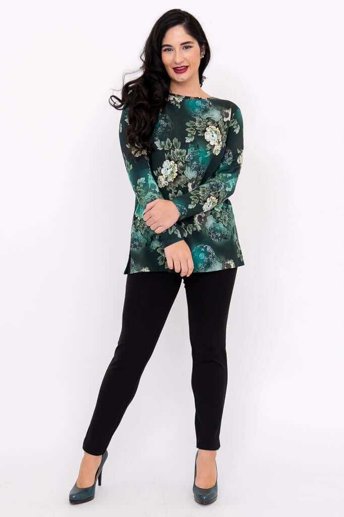 Woman posing in a green floral tunic top and black slim pants