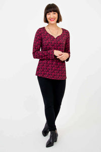 Woman posing in maroon floral sweetheart top and black pants