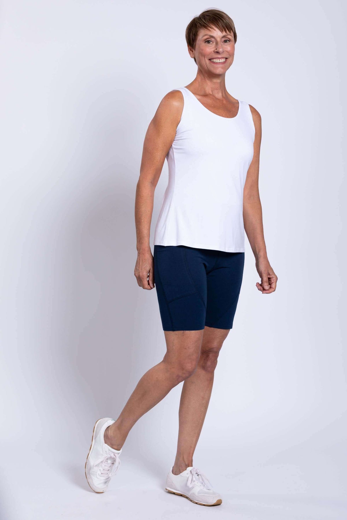 Woman posing in navy Robson Shorts and white sleeveless top, stepping forward