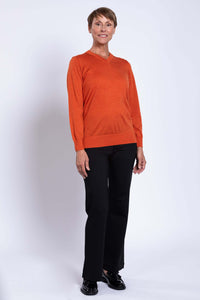 Woman posing in orange V-neck sweater and black dress pants