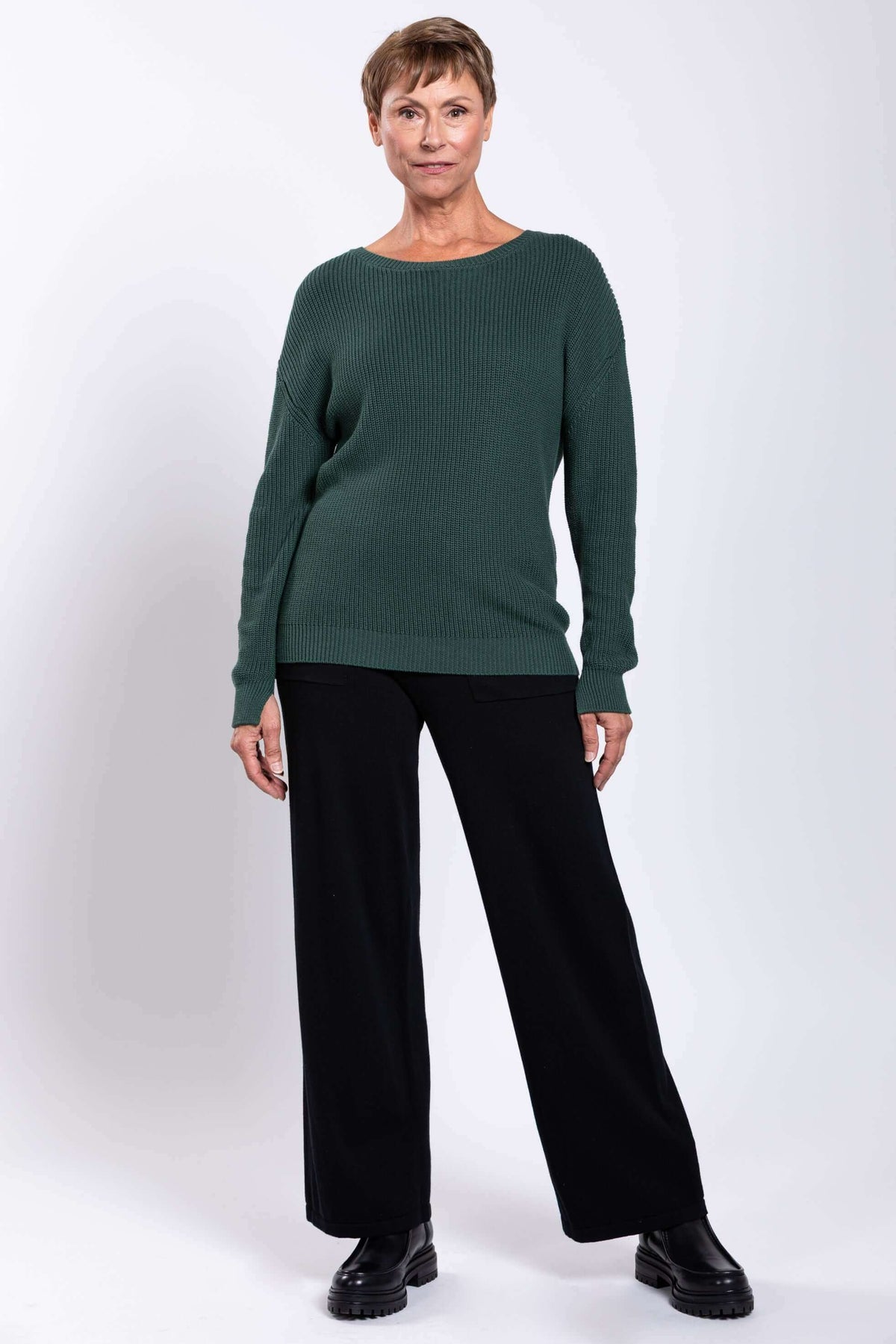 Woman posing in relaxed fit green sweater with black pants