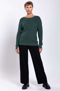 Woman posing in relaxed fit green sweater with black pants