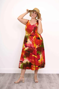 Woman smiling and posing with a sunhat in a sleeveless multicolor abstract midi dress