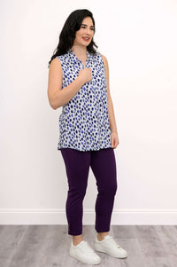 Woman posing sideways in sleeveless blue dot print tank top and purple pants