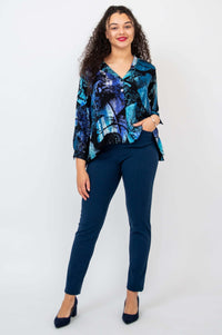 Woman posing with one hand in pocket, wearing blue abstract cropped blouse and navy pants