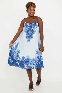 Woman holding out a breezy blue tropical print dress, showcasing the flared hem