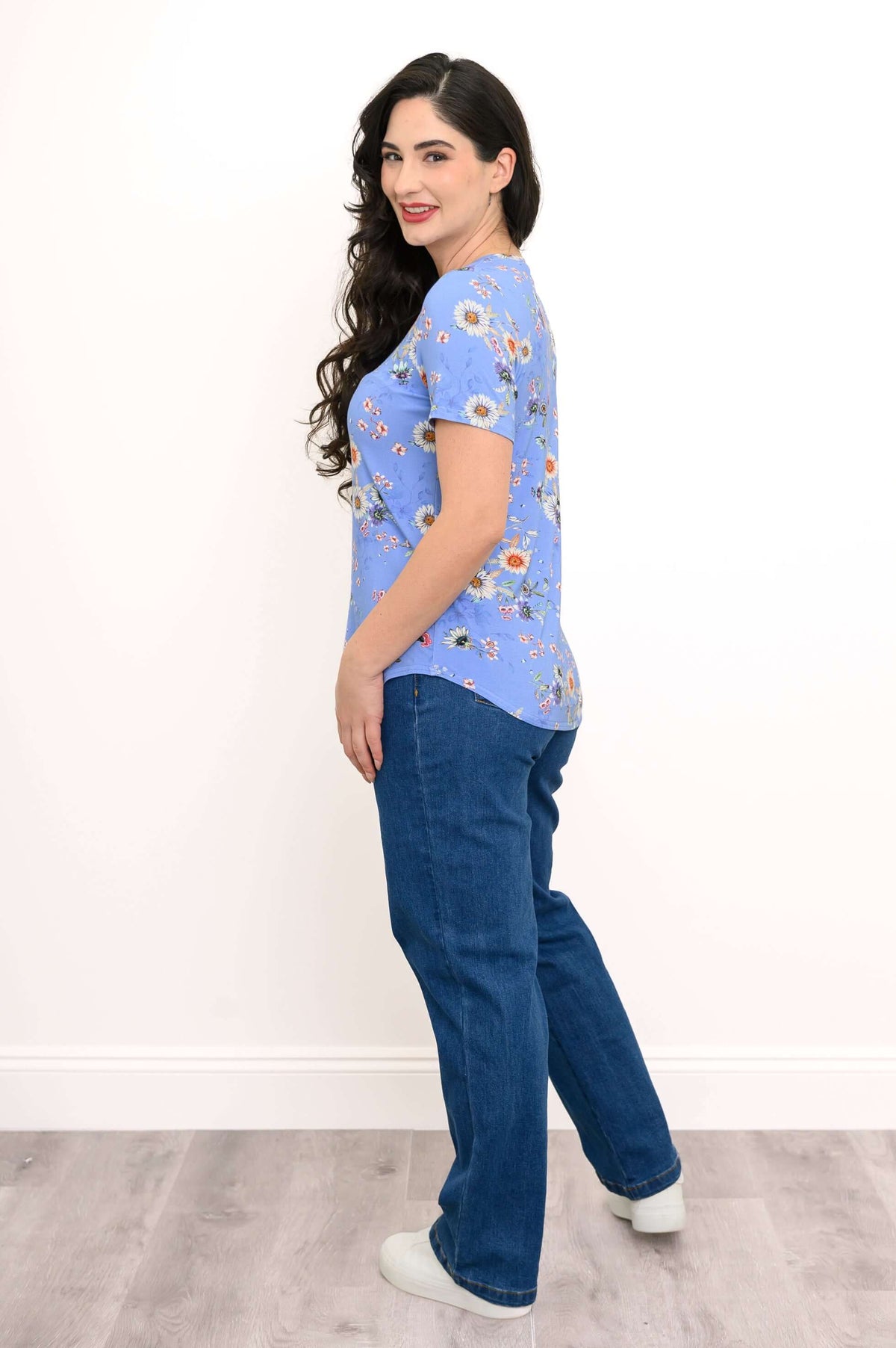 Woman showing a back and side view of a blue floral rounded-hem tee and blue jeans