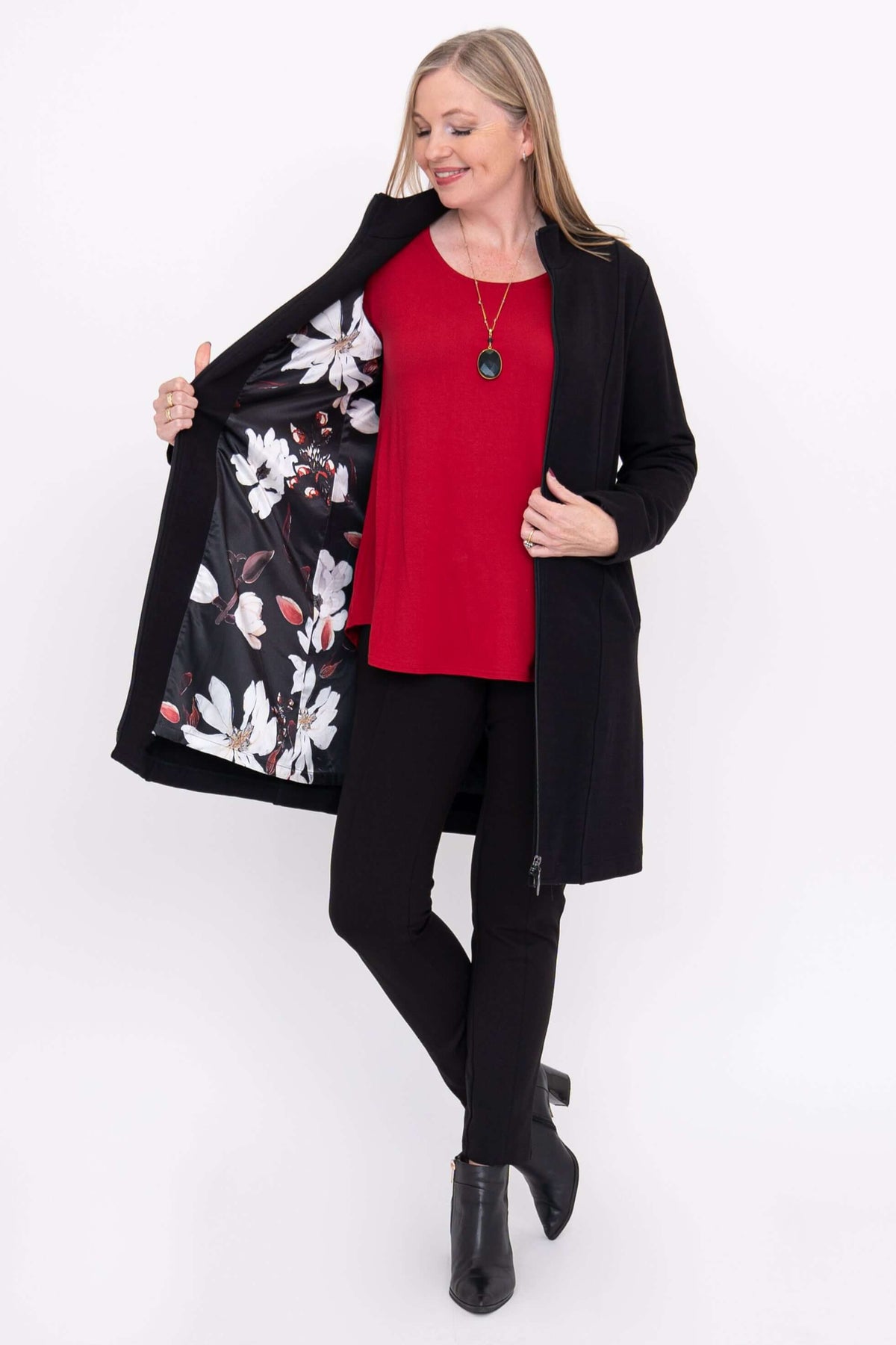 Woman showing floral interior lining of black coat and wearing red top