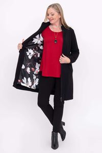 Woman showing floral interior lining of black coat and wearing red top