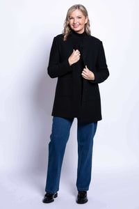 Woman smiling and holding open front of her black boiled wool coat, showing hidden snaps