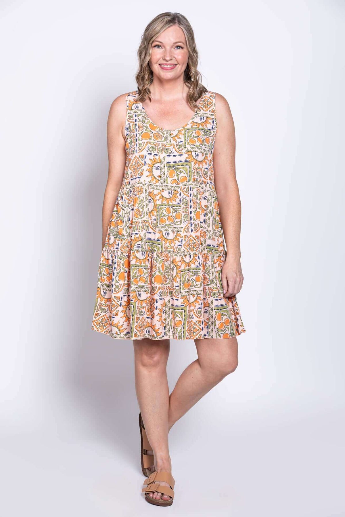 Woman modeling a scoop neck, tiered sundress with a colorful abstract pattern
