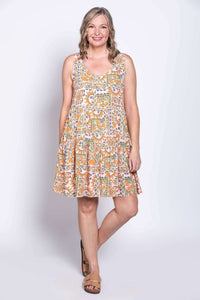 Woman modeling a scoop neck, tiered sundress with a colorful abstract pattern