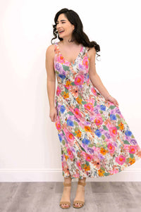 Smiling woman holding the skirt of a bright floral maxi dress, showing movement