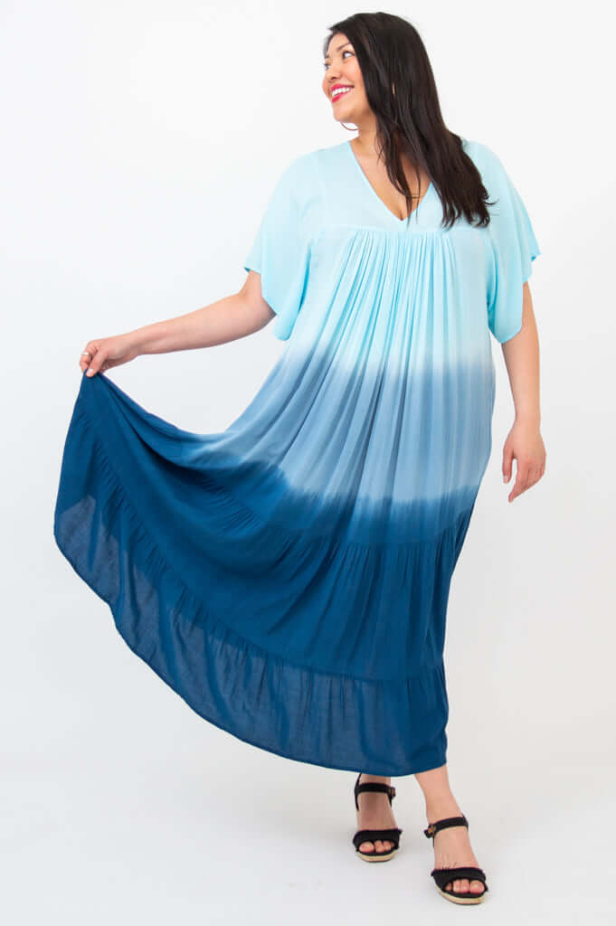 Woman displaying the wide skirt of ombre blue and navy tiered maxi dress