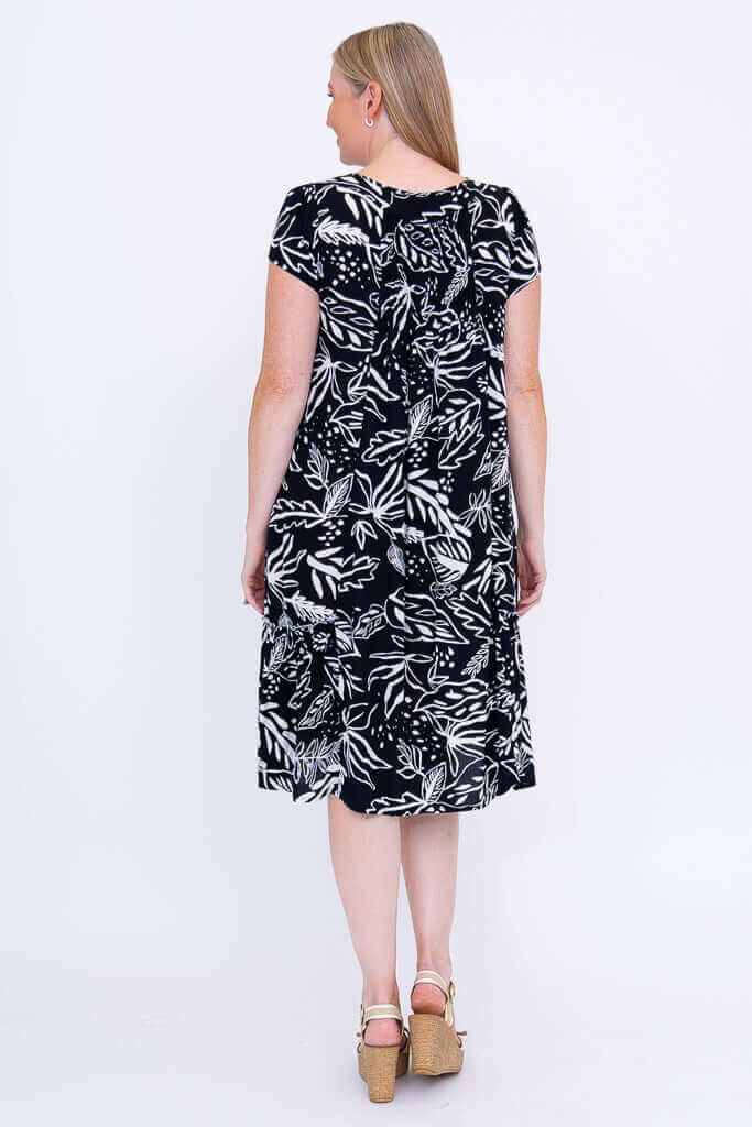 Woman showing the back view of a black and white leaf print dress