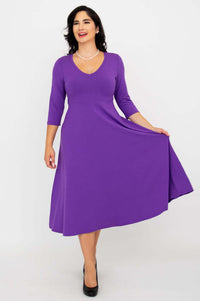 Woman showing the flowy A-line skirt of a purple three-quarter sleeve midi dress