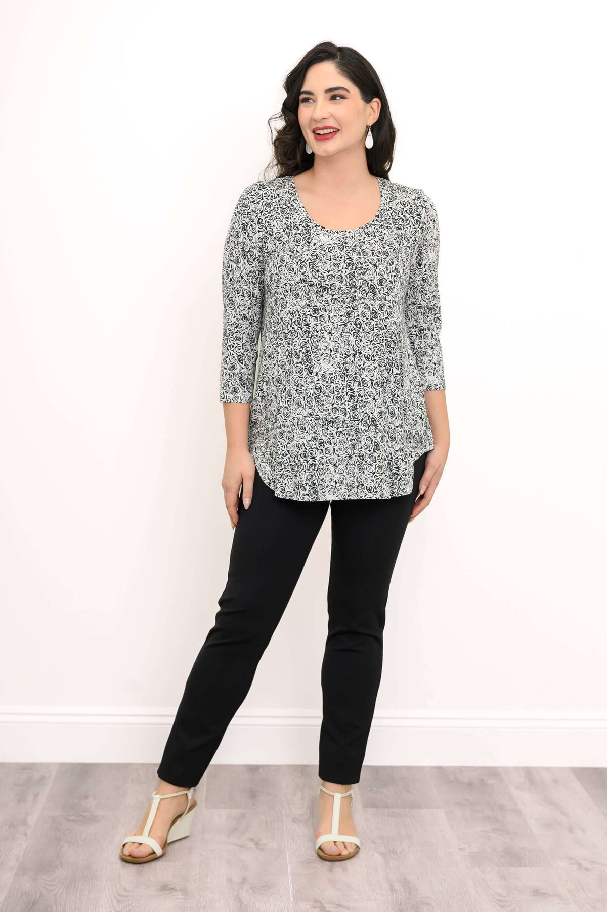 Woman smiling and wearing black and white rose bamboo top with black pants