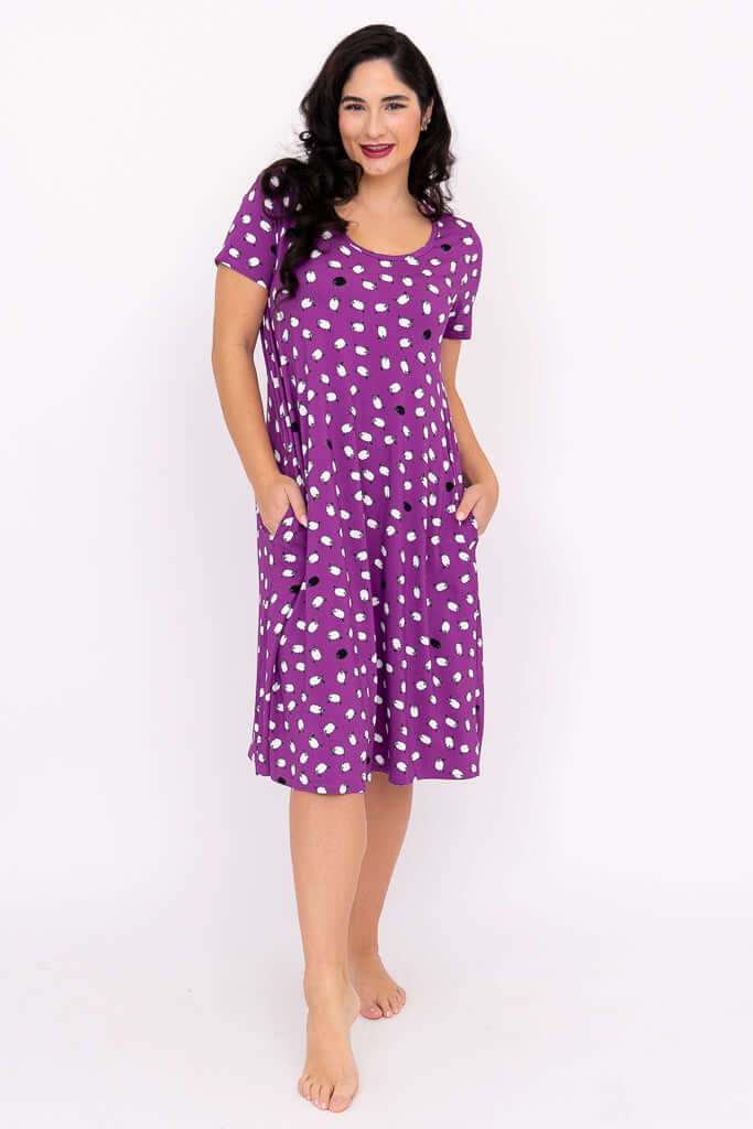 Woman smiling in a purple dot sleepshirt with hands in pockets