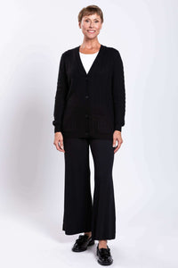 Woman smiling in a black cable knit cardigan and black pants with tassel loafers