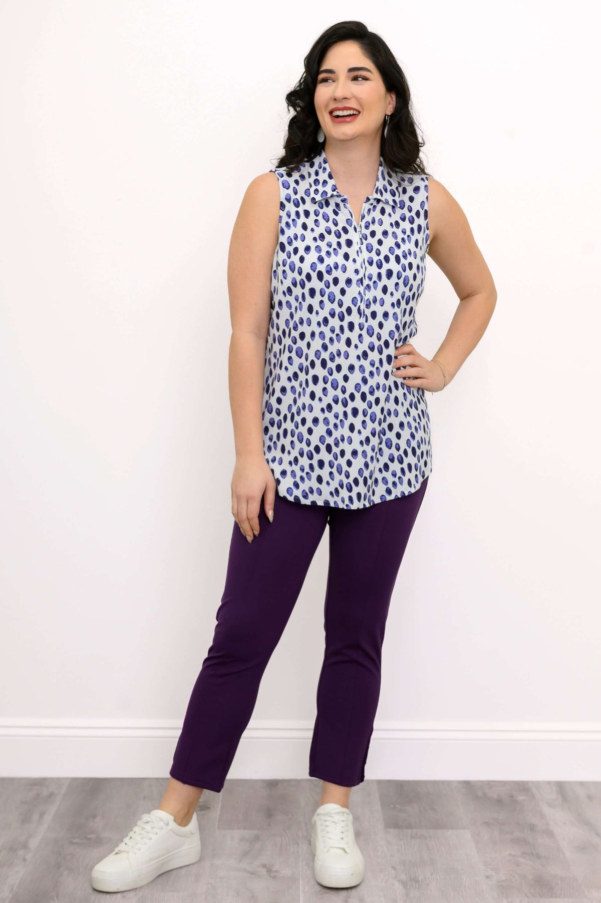 Woman smiling in blue dot print sleeveless tank top with hand on hip