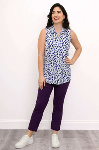 Woman smiling in blue dot print sleeveless tank top with hand on hip