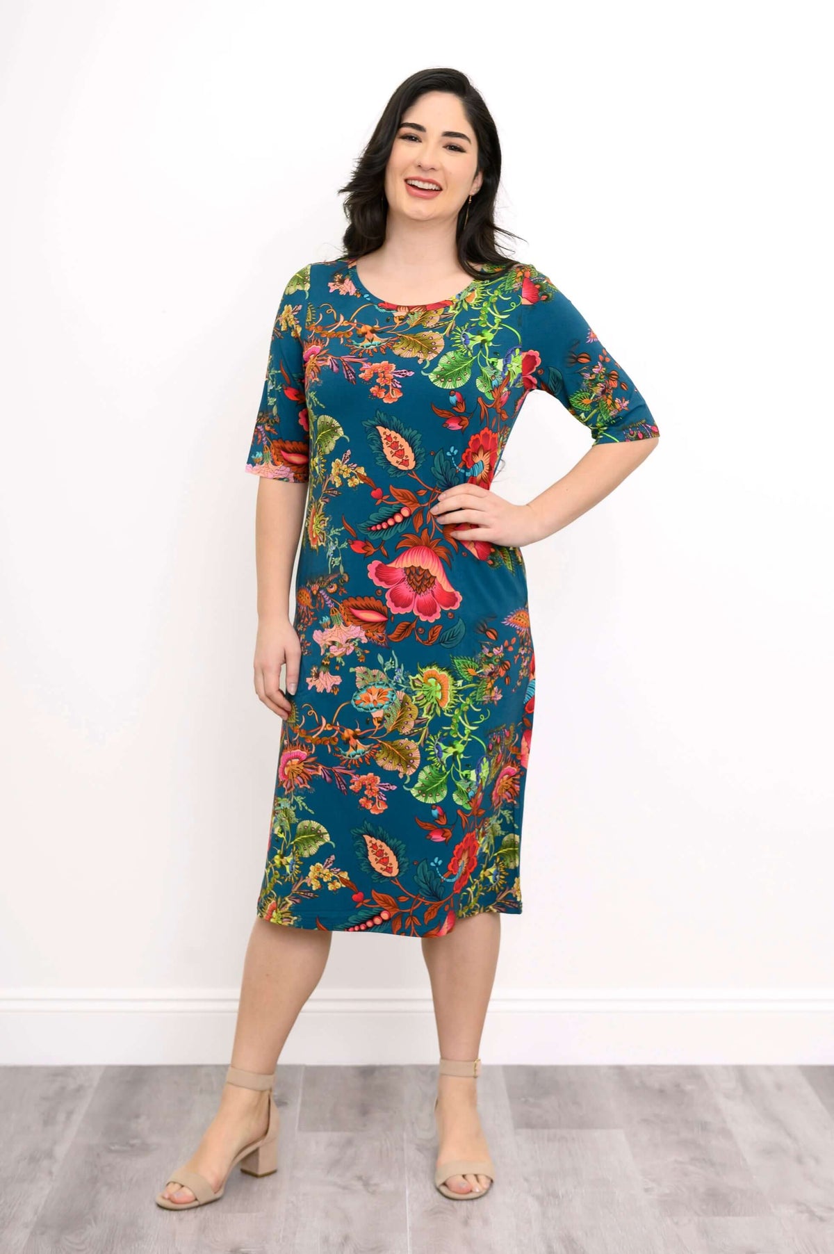 Smiling woman wearing a knee-length teal bamboo dress with bright floral print