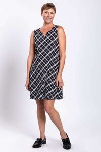 Woman smiling in sleeveless plaid shift dress with black shoes