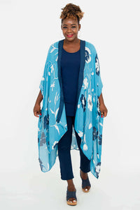 Woman smiling, modeling blue floral Darcy wrap, hands by sides