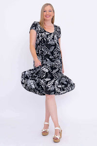 Woman spinning in a black and white leaf print dress showing the flowy skirt