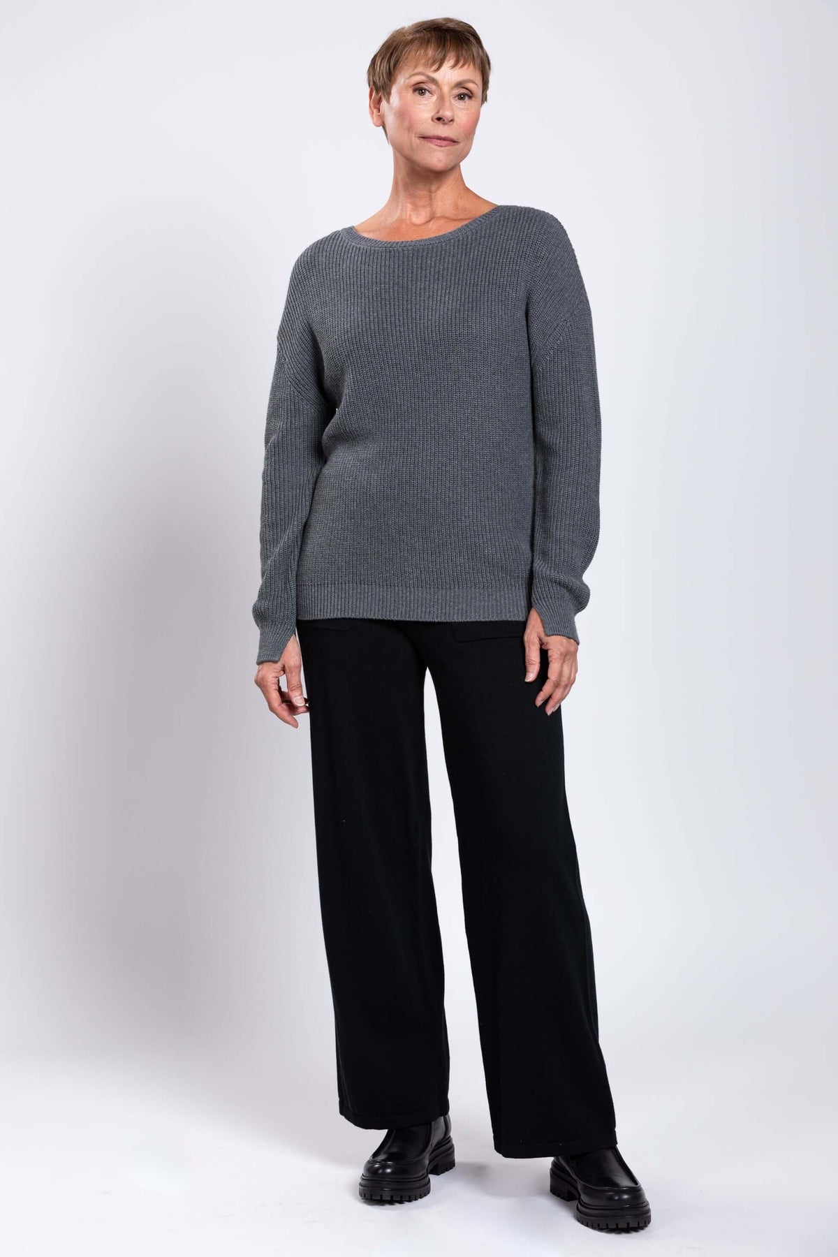 Woman standing at an angle in gray shaker stitch sweater and black pants