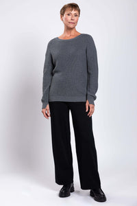Woman standing at an angle in gray shaker stitch sweater and black pants