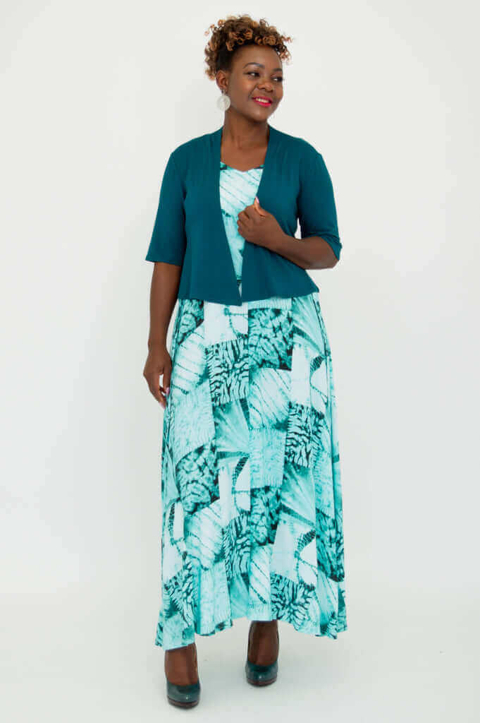 Woman standing at angle, hand to chest, modeling teal cropped Doda Jacket