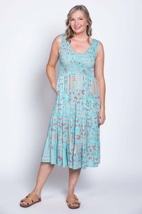 Woman standing in a blue floral print sleeveless midi dress with hands in pockets