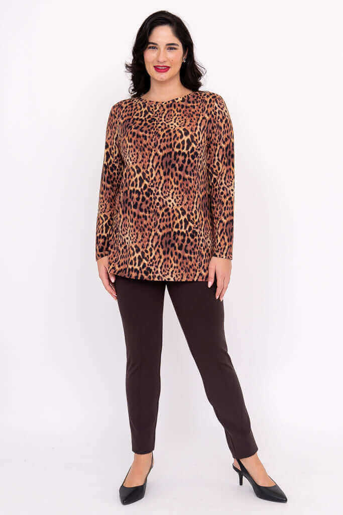 Woman standing in a leopard print top and brown pants, facing front