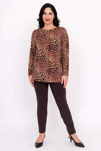 Woman standing in a leopard print top and brown pants, facing front