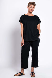 Woman standing in black linen blend tee and wide-leg pants, casual sandals, front view