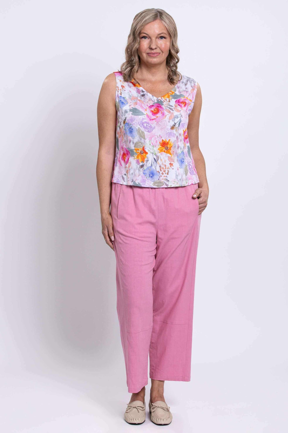 Woman standing in floral V-neck tank and pink high-waisted pants