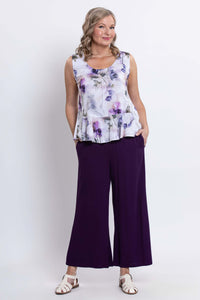 Woman standing in a purple floral tank top with wide-leg purple pants and white sandals