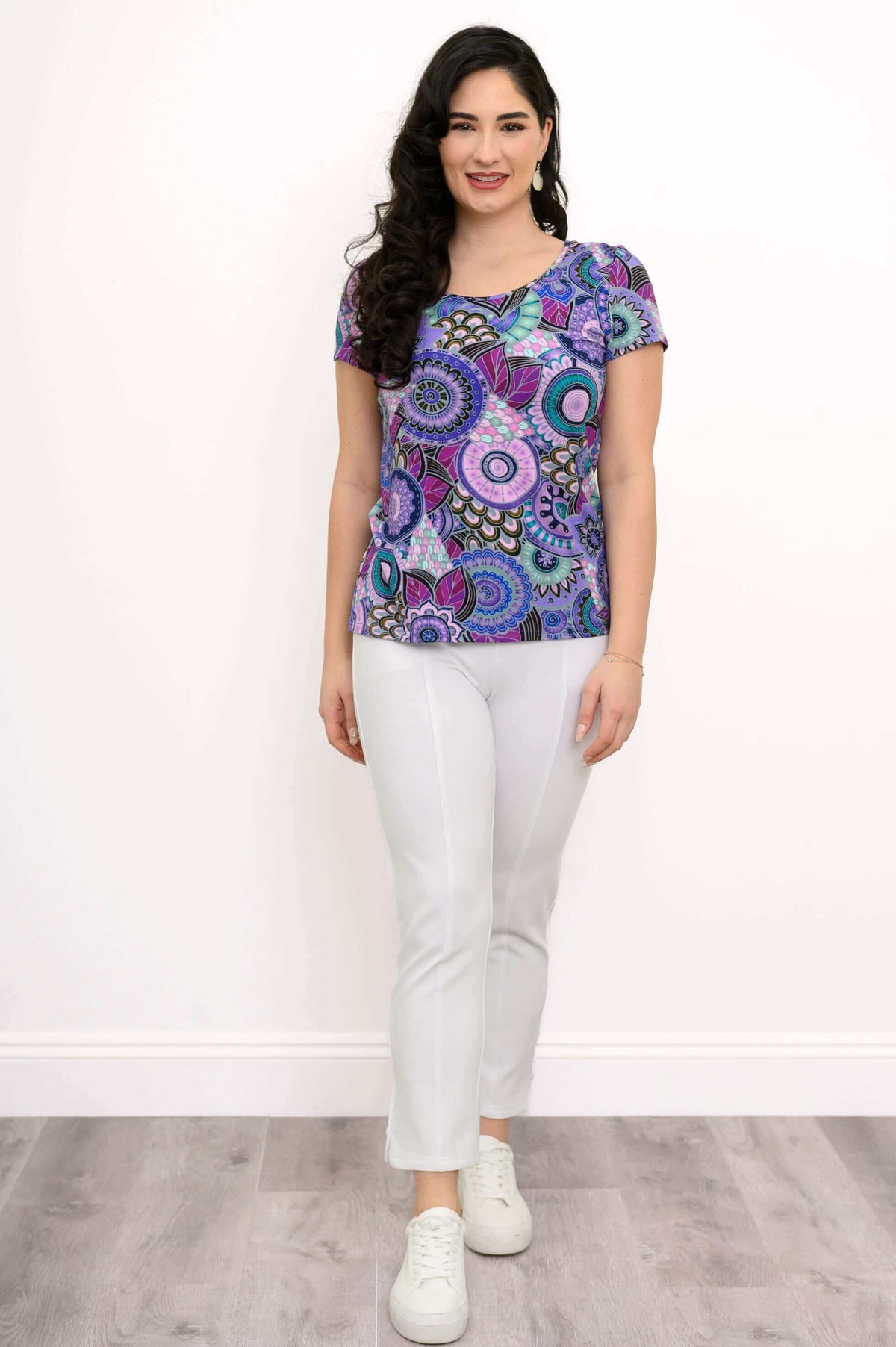 Woman standing straight in a purple mandala bamboo top and white pants