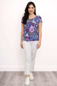 Woman standing straight in a purple mandala bamboo top and white pants
